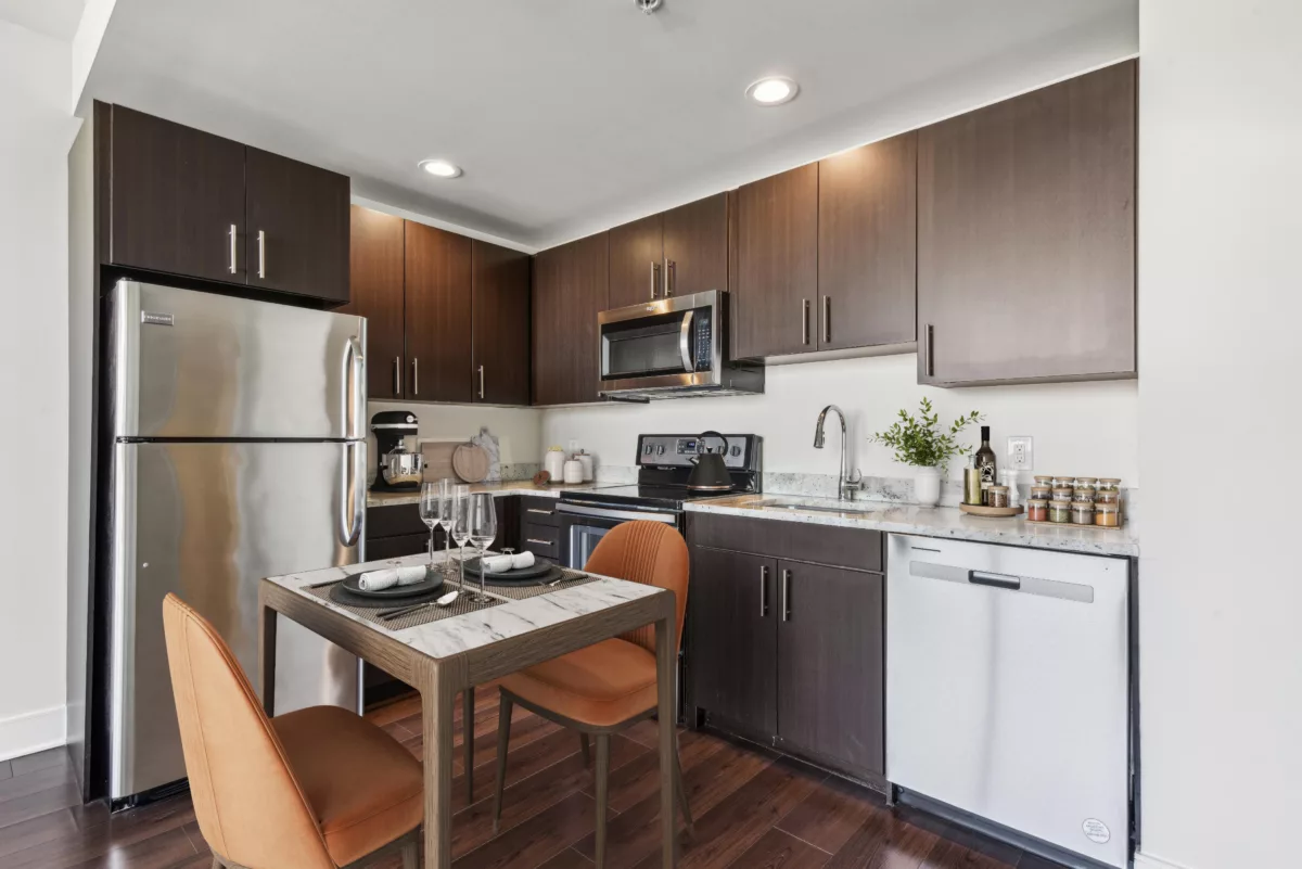 Kitchen with stainless steel appliances, dark cabinets, and dining table.