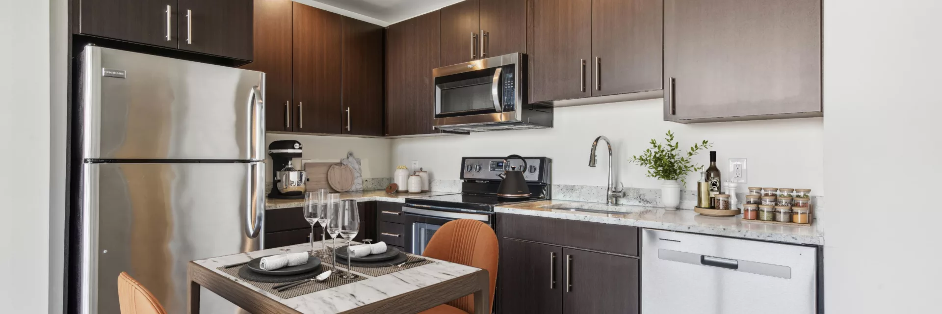 Kitchen with stainless steel appliances, dark cabinets, and dining table.