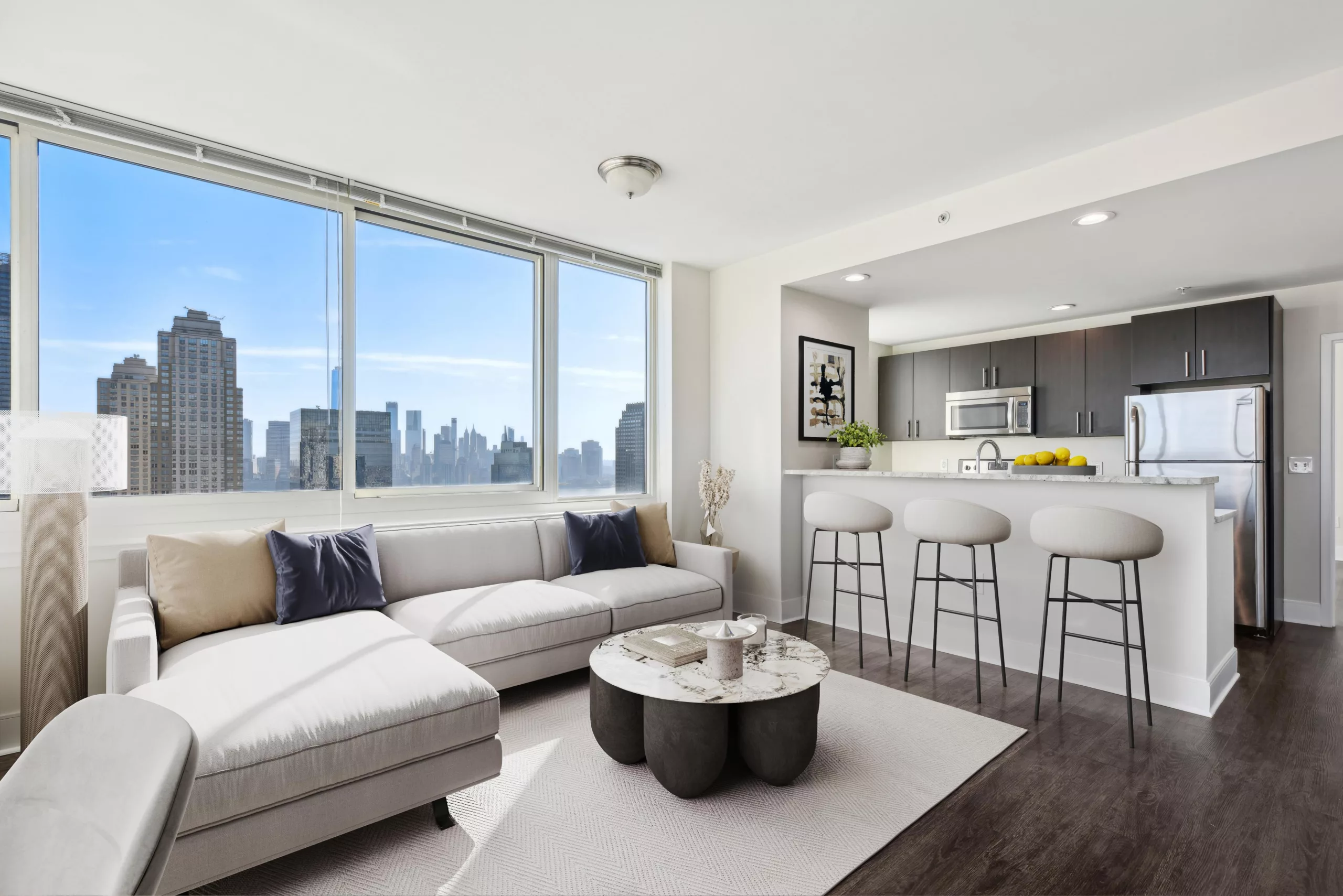 Living room with white sofa and large windows overlooking a city skyline.