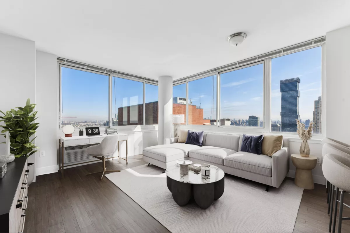 Living room with white sofa and large windows overlooking a city skyline.