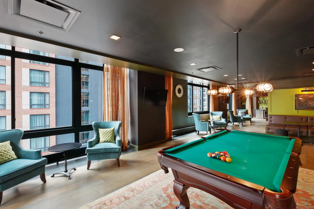 Lounge with pool table, armchairs, bar area, and large windows.