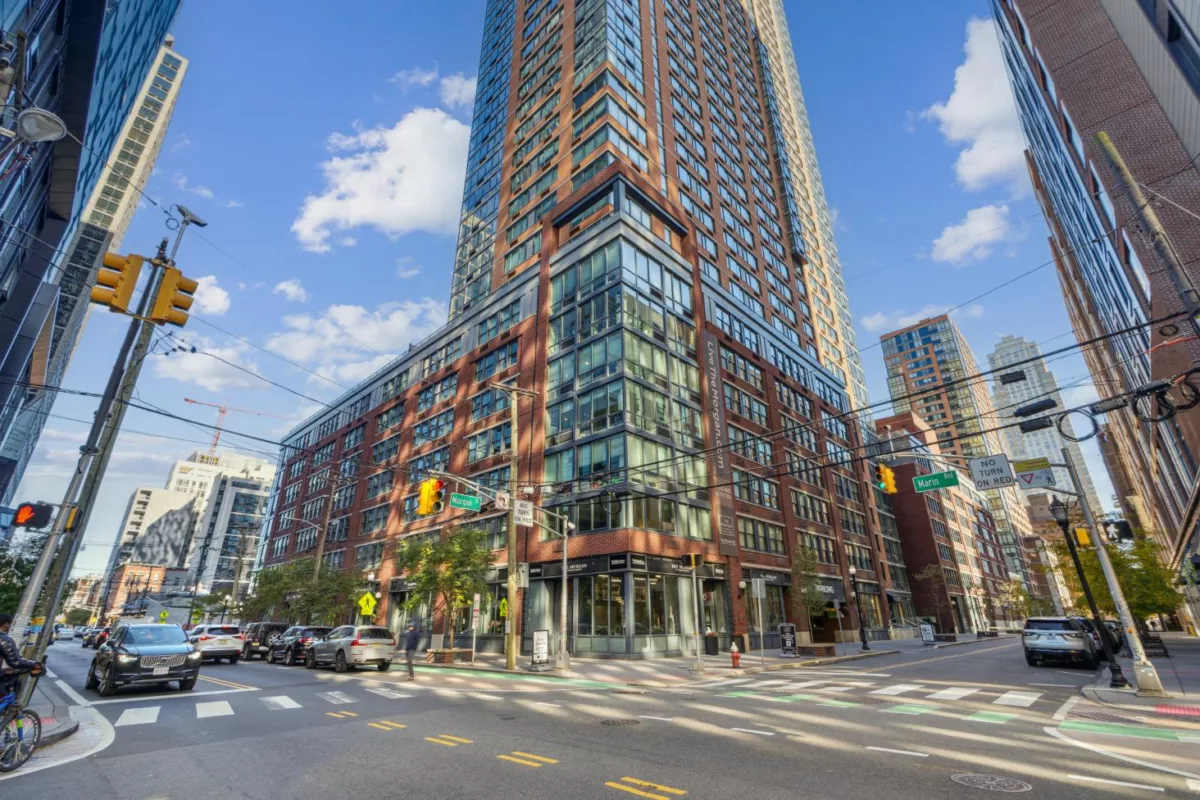 Corner view of tall modern residential building at busy urban intersection.