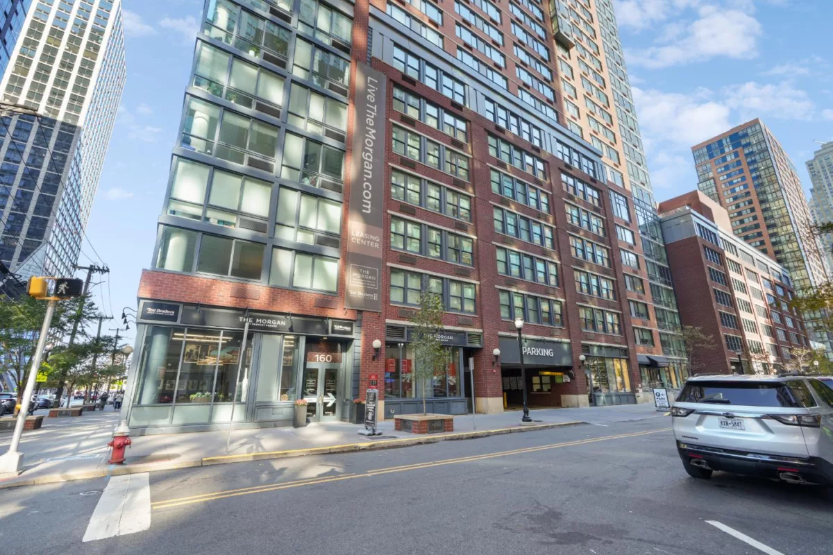 Street-level view of red brick apartment building with leasing office entrance.