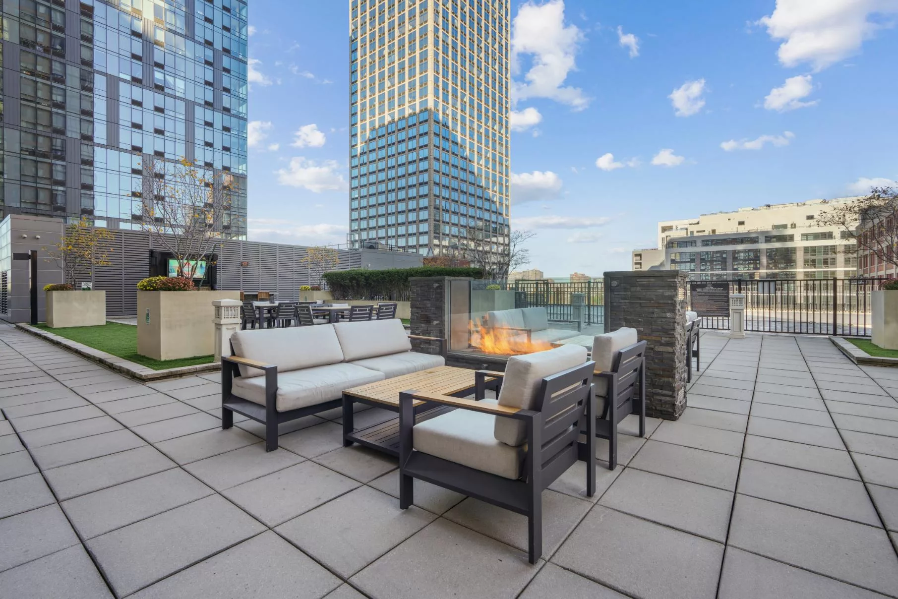 Outdoor lounge with firepit and cushioned seating on a rooftop terrace.