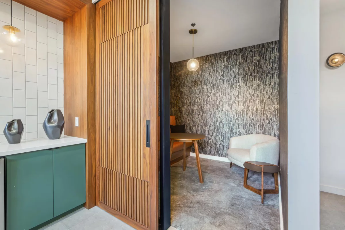 Small seating alcove with textured wall, wood table, and upholstered chairs.