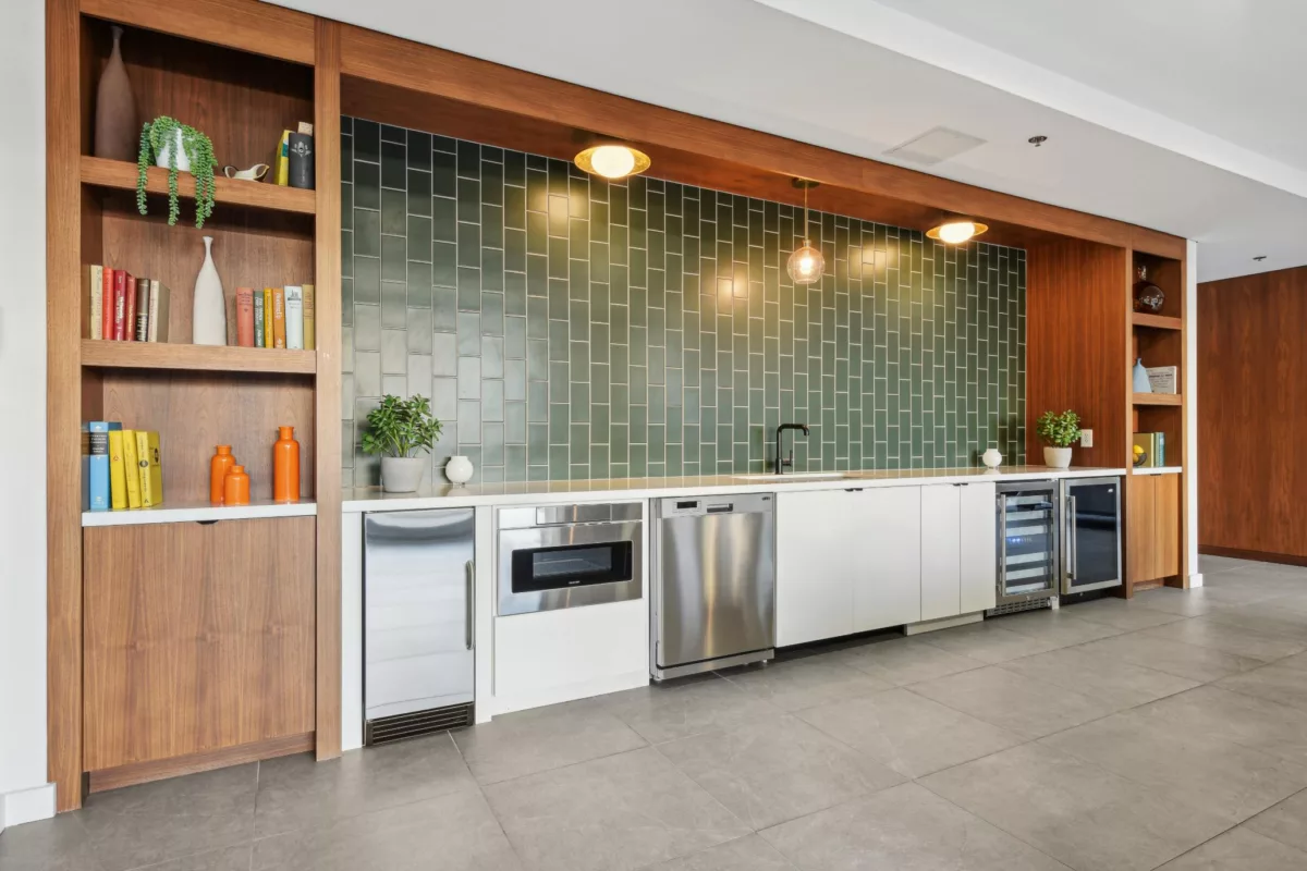 Close-up of modern kitchen with green tile wall and stainless appliances.