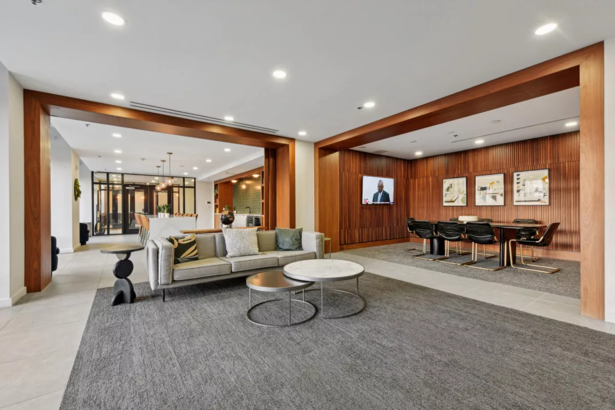 Lounge with sofa, TV, and conference table in a wood-accented room.