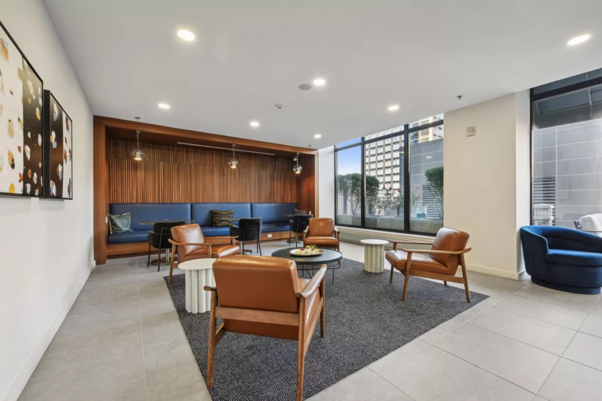 Lounge area with leather chairs, blue bench seating, and large windows.