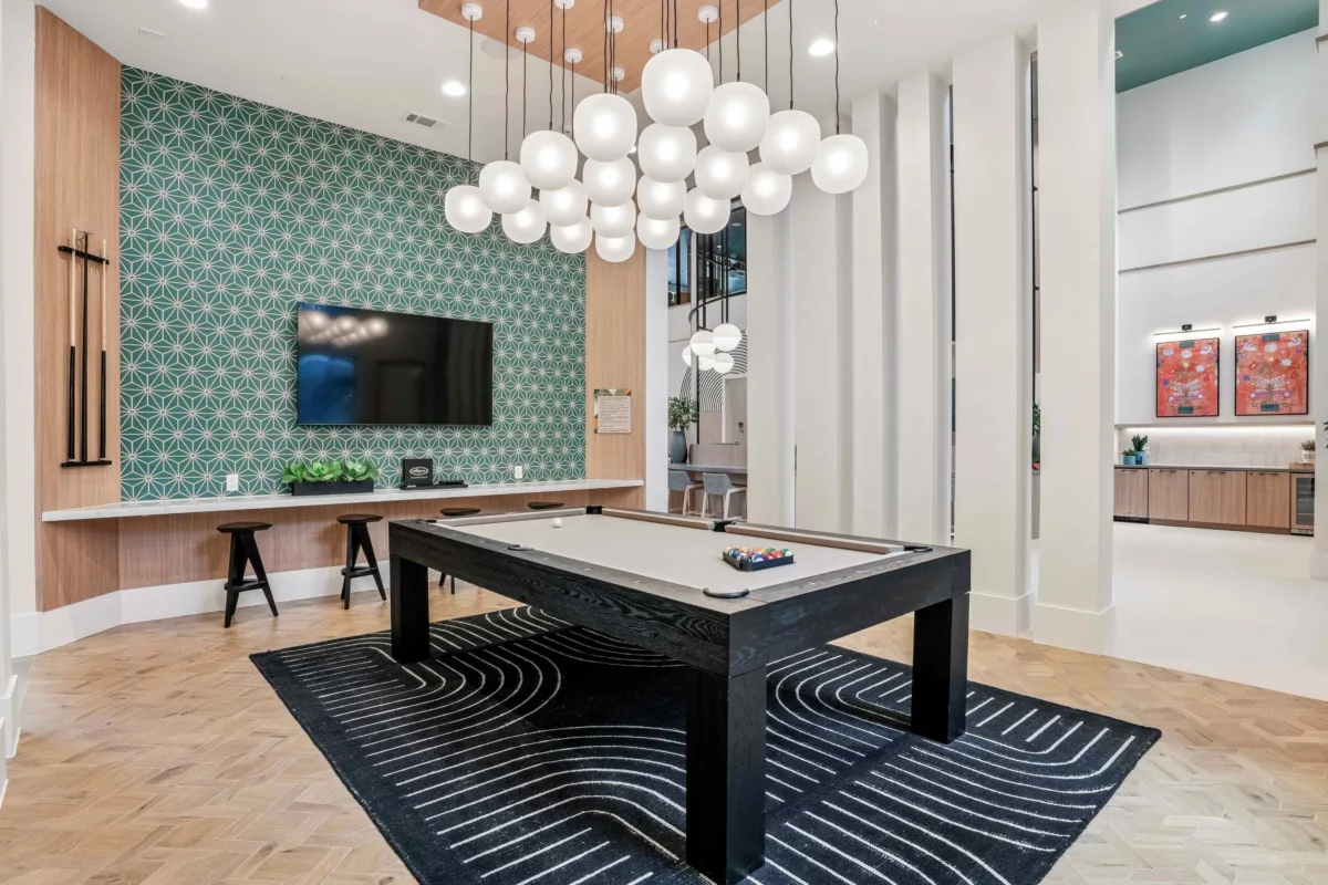 Game billiards lounge with pool table, stools, geometric wallpaper, and modern lighting fixtures.