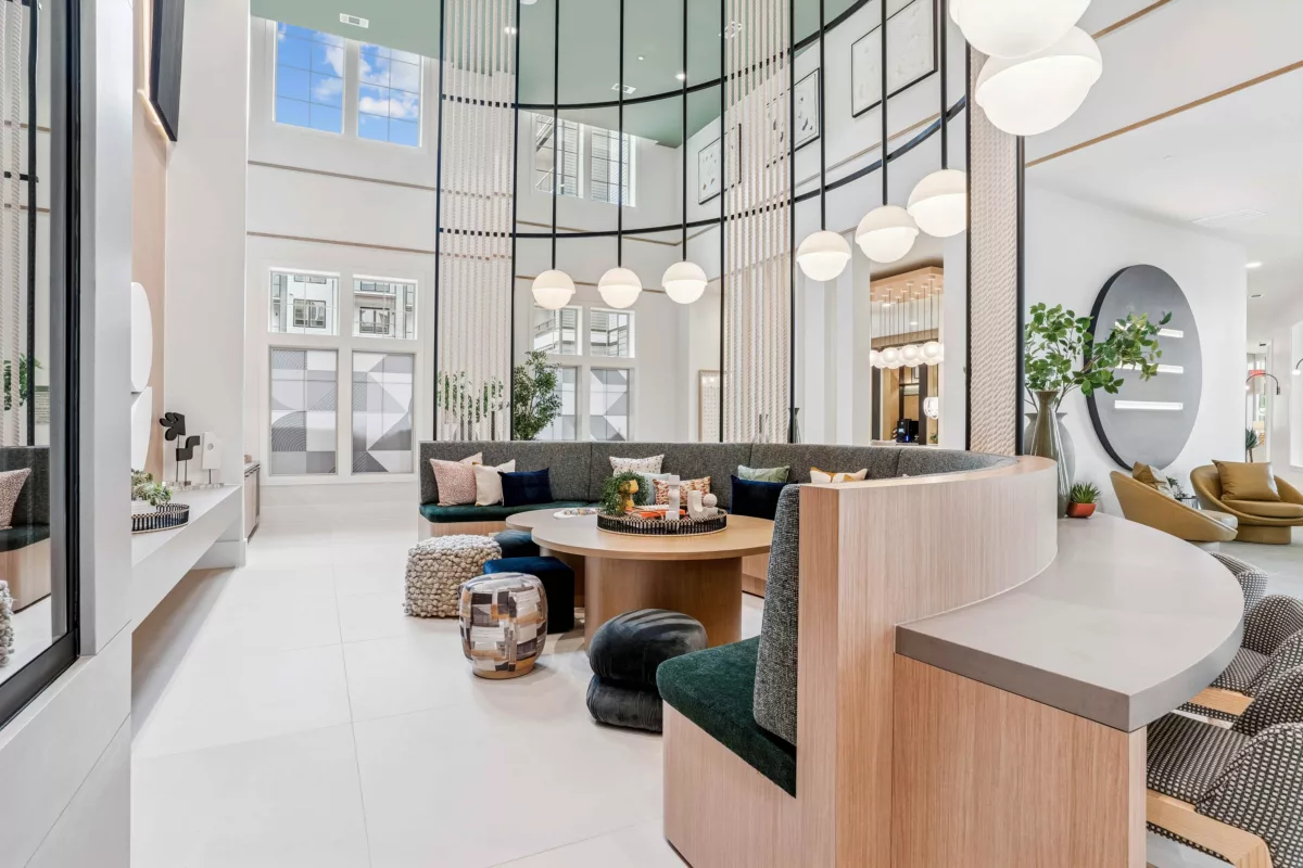 Clubroom with curved seating, round tables, pendant lighting, and double-height windows.