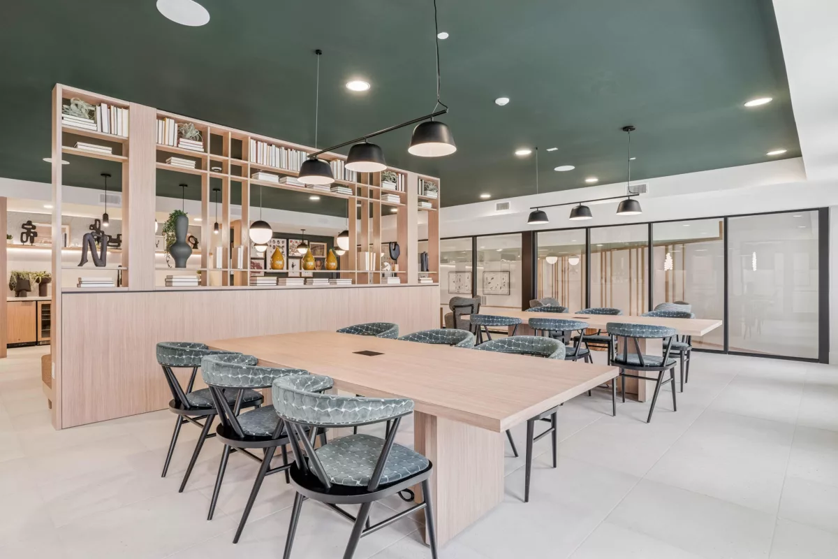 Coworking space with tables, chairs, and shelving filled with books and decor.