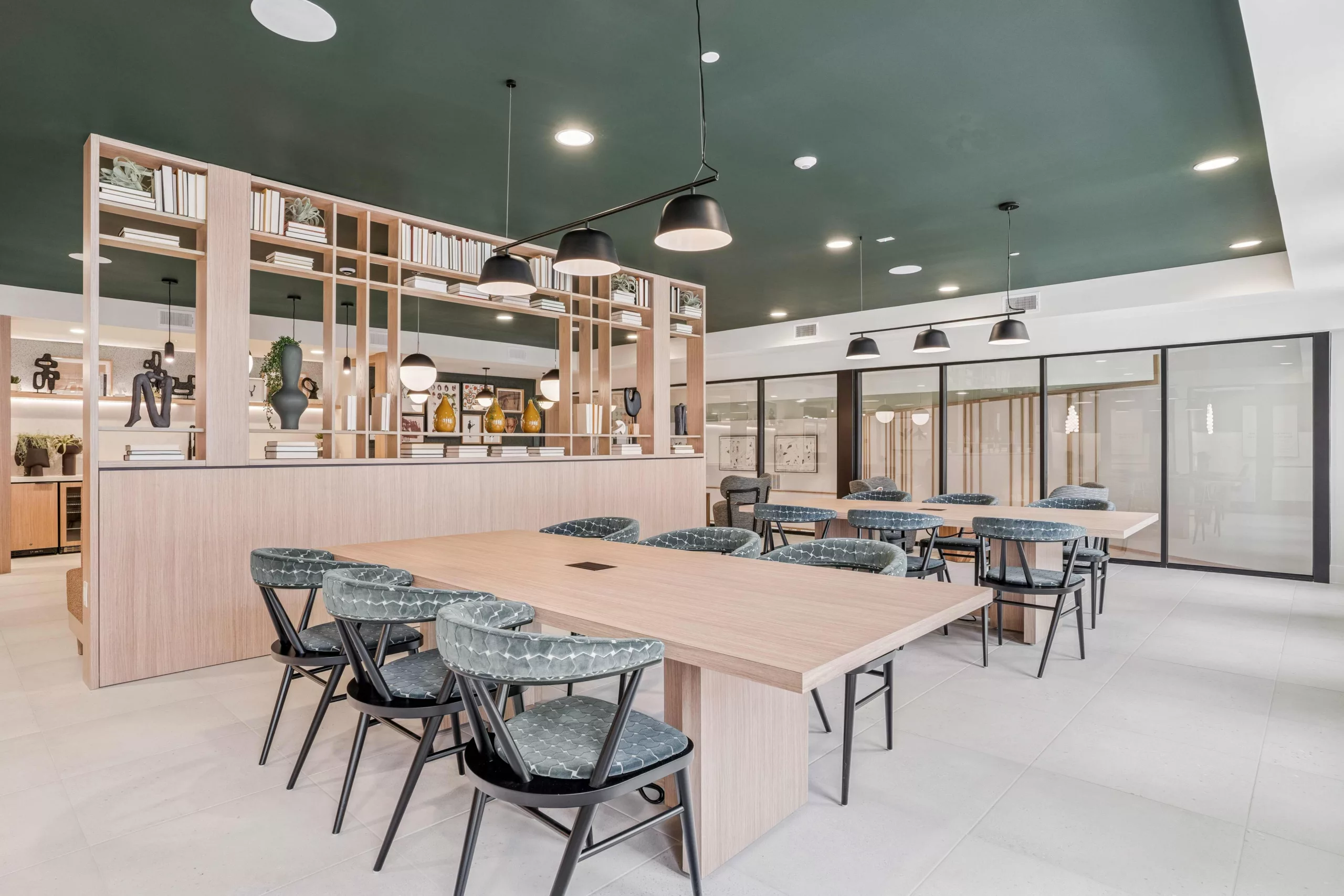 Coworking space with tables, chairs, and shelving filled with books and decor.