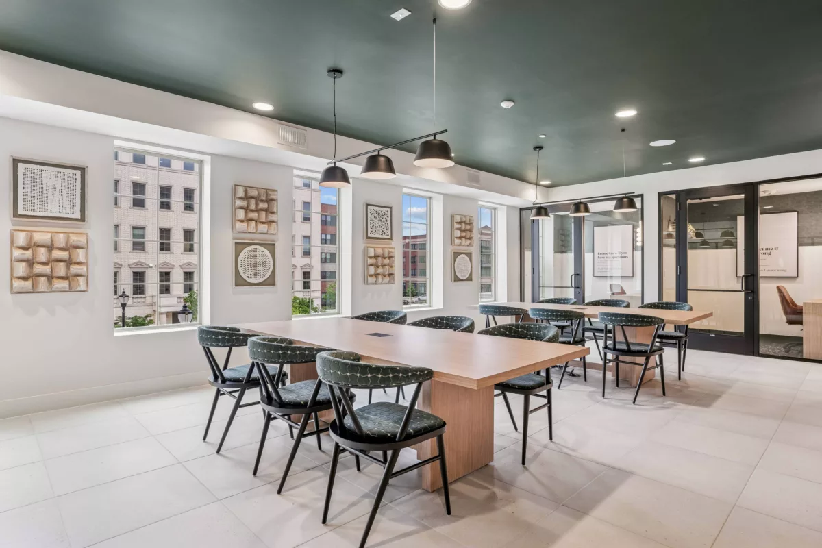 Coworking lounge with conference tables, chairs, and large windows.