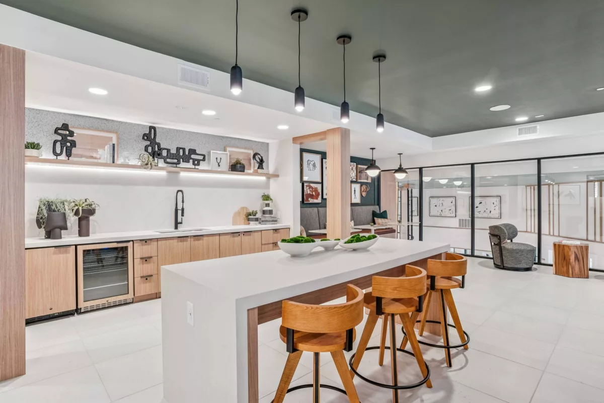 Coworking lounge with island seating, wood cabinets, and decorative shelving.