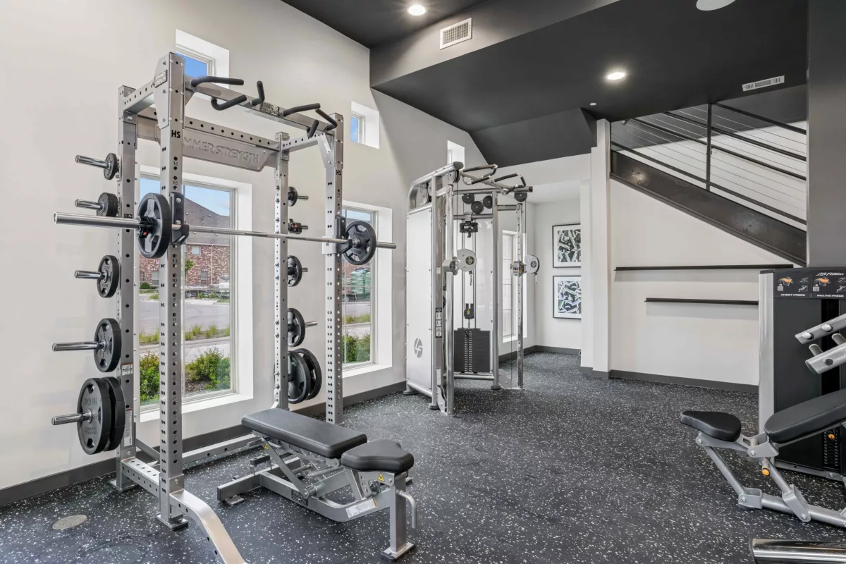 Fitness center with weight rack, bench, cable machine, and rubber flooring.