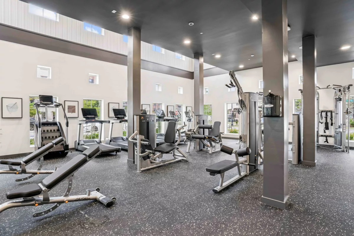 Fitness center with treadmills, weight machines, and rubber flooring.