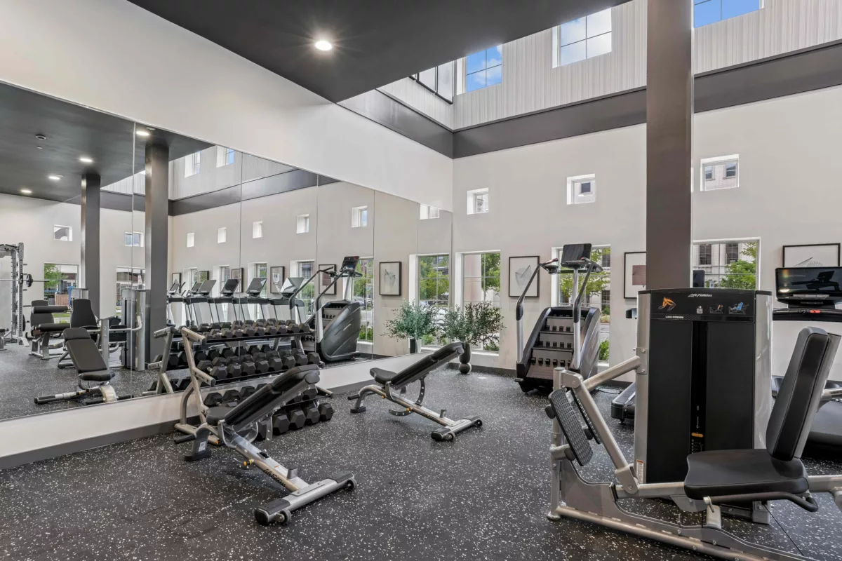 Fitness center with treadmills, weights, and weight machines and two stories of windows.
