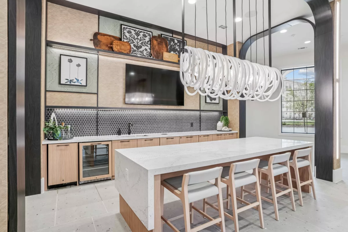 Resident bar lounge with island, bar seating, cabinets, and decorative shelving.