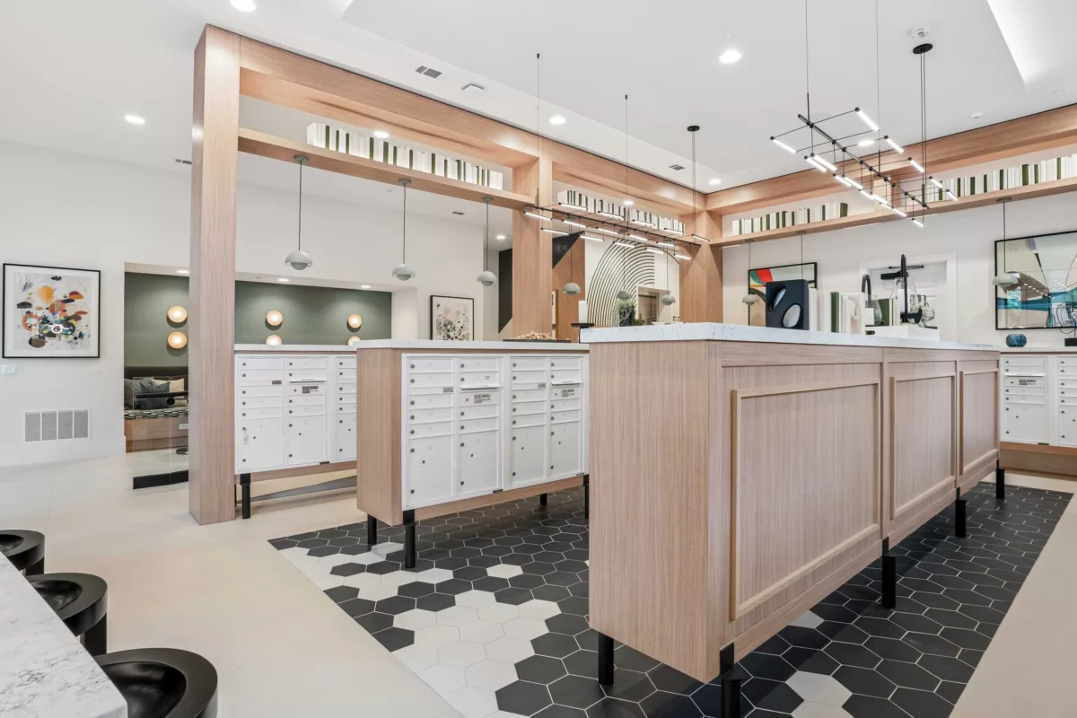 Social mailroom with white mailboxes, wood accents, geometric tile flooring, and contemporary lighting.