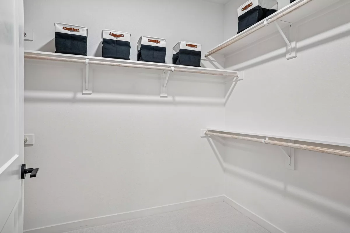 Oversized closet with white walls, carpet, shelving, and storage bins.