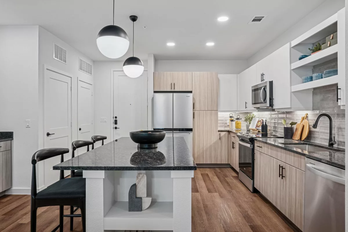 Modern kitchen with granite island, stainless steel appliances, and wood-look flooring.