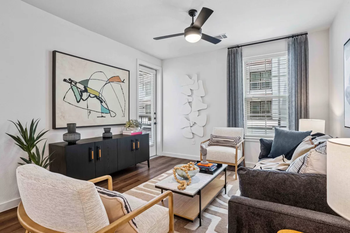 Living room with hardwood floors, sofa, chairs, modern wall art, and a ceiling fan.