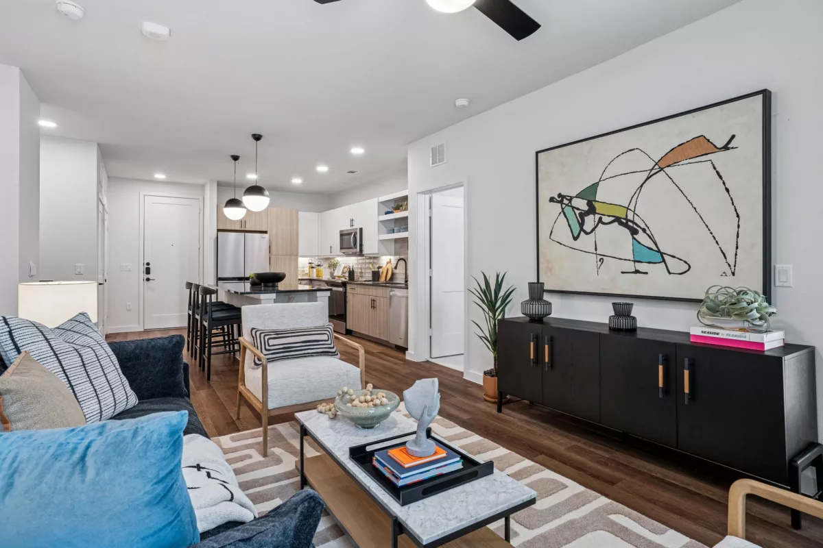 Open-concept living area with kitchen, sofa, chair, coffee table, and dark wood console.