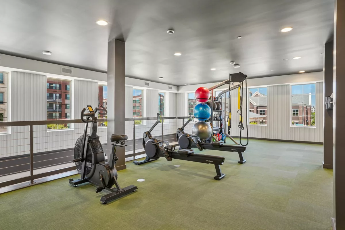 Fitness center with stationary bike, rowing machines, and weight training equipment.