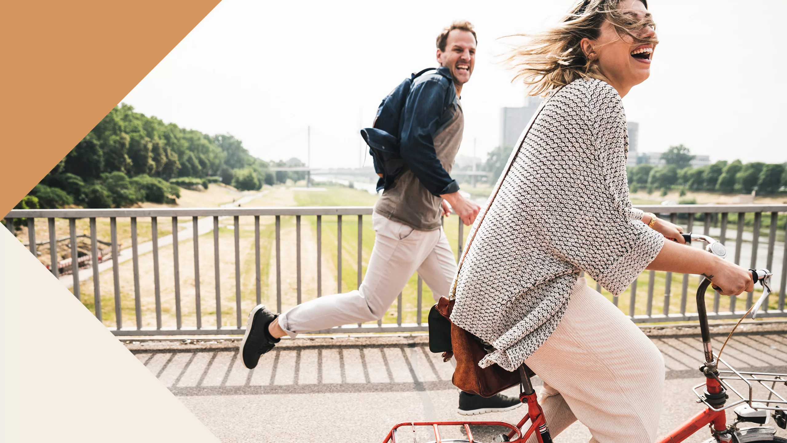 A photo of a woman on a bike and a man running beside her, with decorative orange and beige triangles in the left corners.