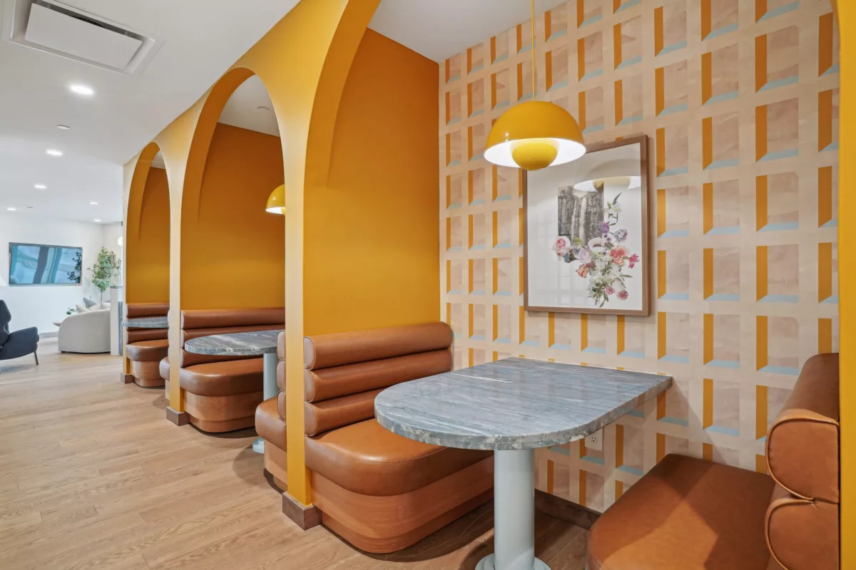 Booth seating with leather benches, yellow arched walls, and patterned wallpaper.