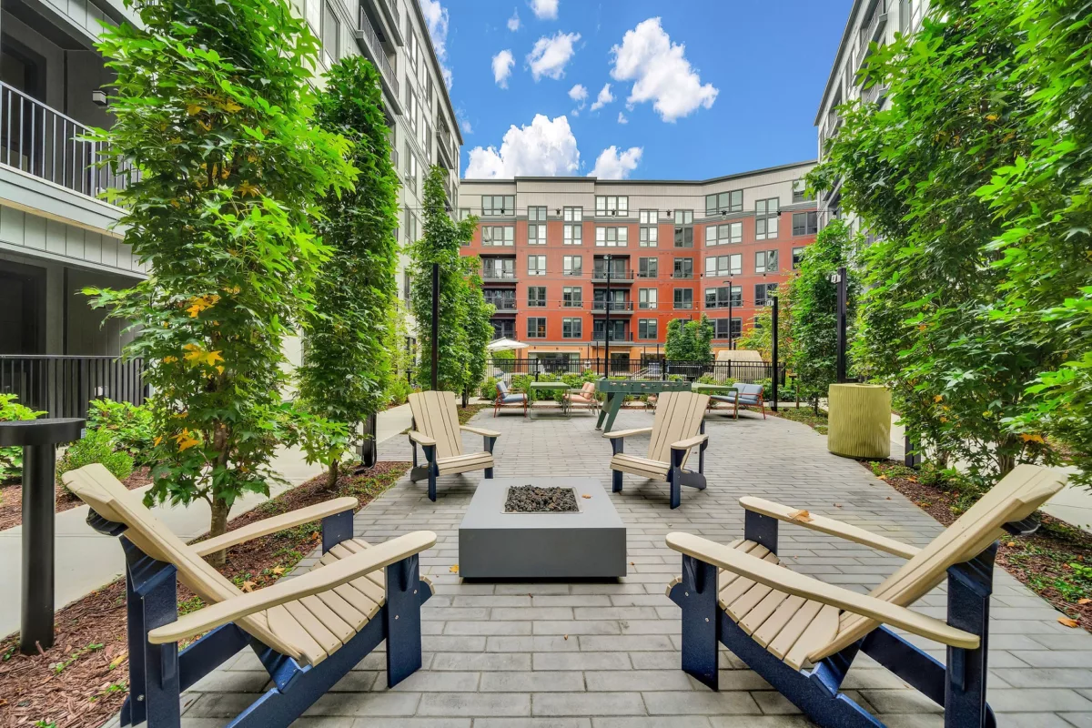 Outdoor courtyard with Adirondack chairs, fire pit, and foosball table between apartment buildings.