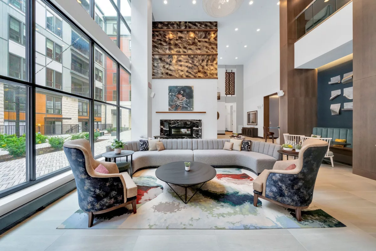 Lounge with curved sofa, armchairs, fireplace, and floor-to-ceiling windows.
