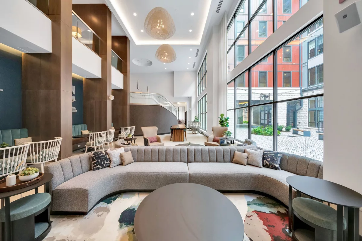 Grand lobby with curved sofa, high ceilings, large windows, and modern design elements.