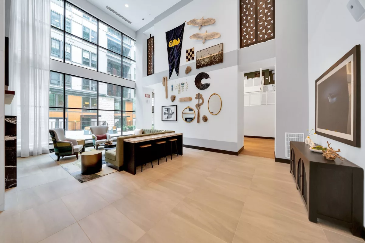 Lobby with high ceilings, large windows, seating, and decorative wall art.