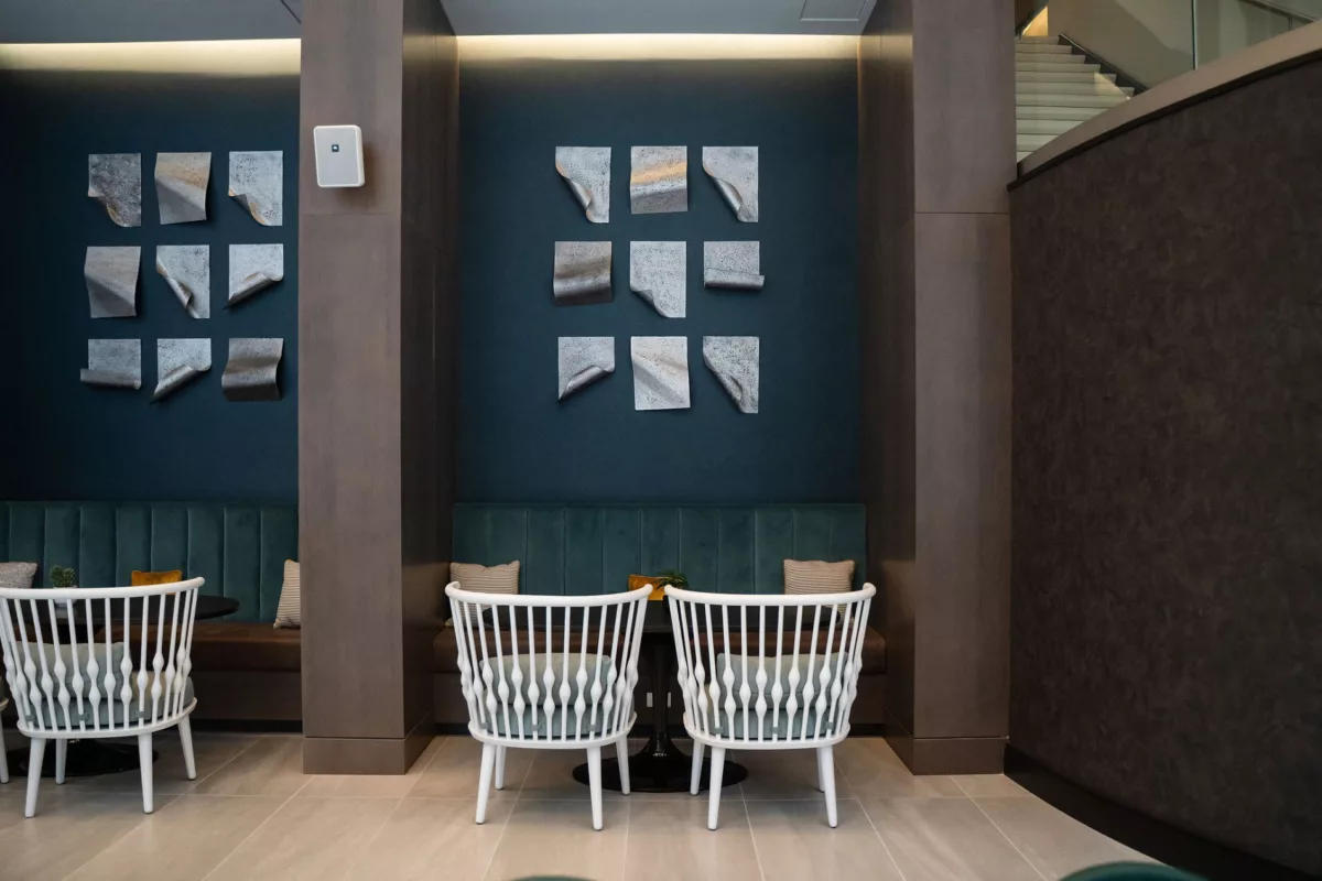 Lounge area with white chairs, booth seating, and decorative wall art on a dark blue wall.