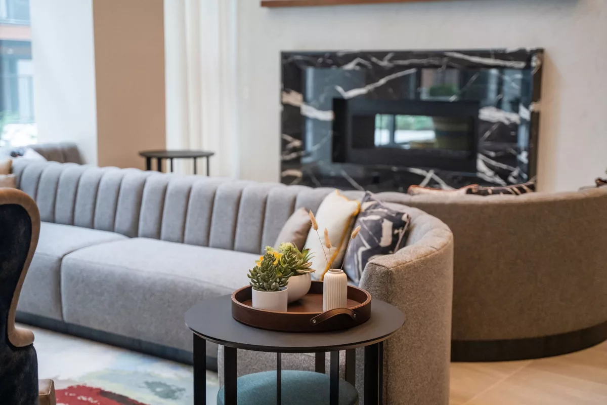 Lounge area with gray sofas, black marble fireplace, and round side table with decor.