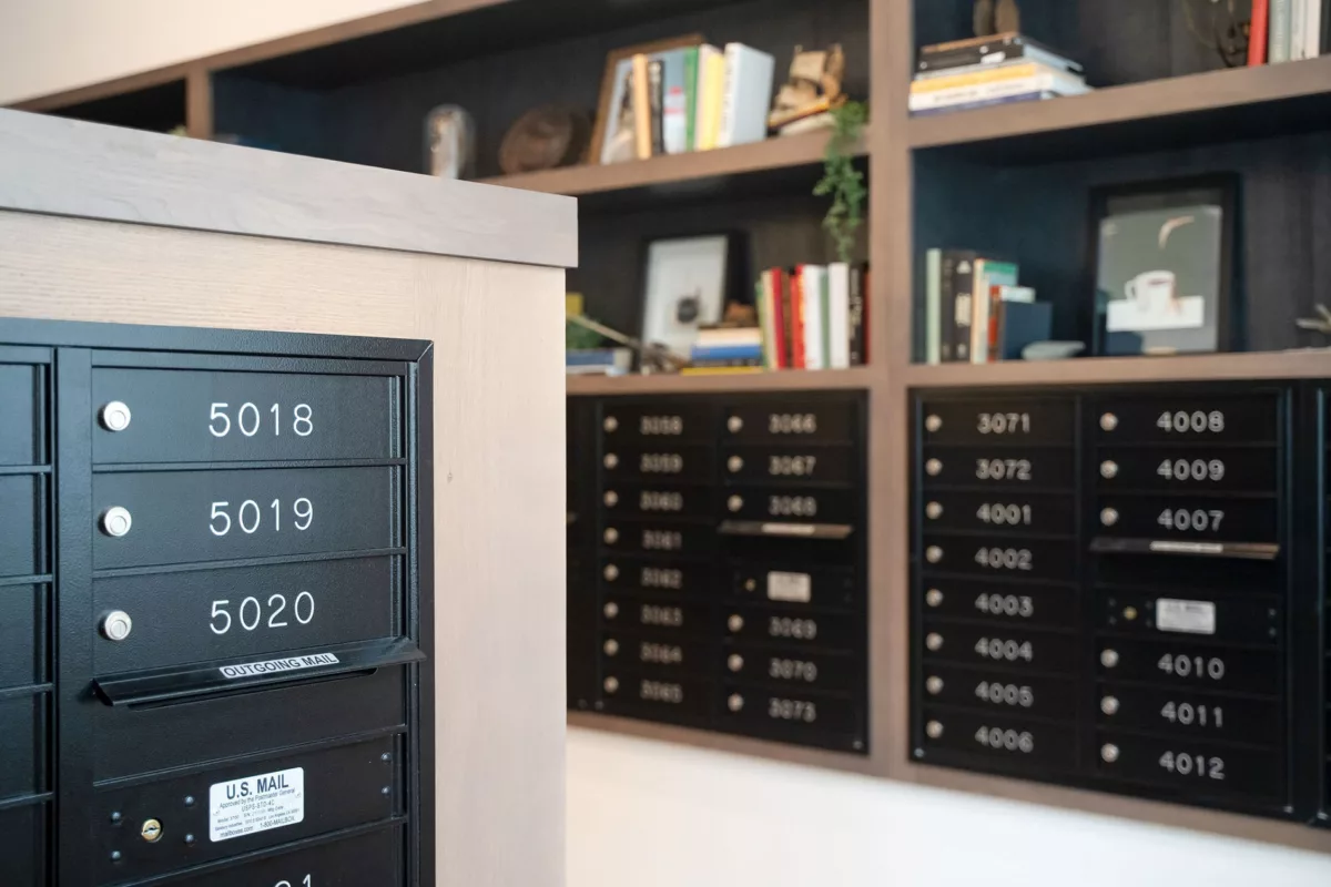 Mailboxes with unit numbers in a common area with built-in shelving and decorative items.