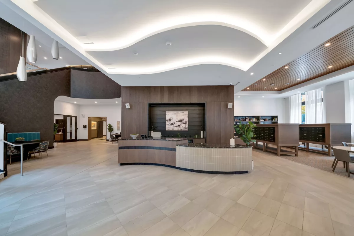 Grand lobby with reception desk, mailboxes, seating, and decorative ceiling lighting.