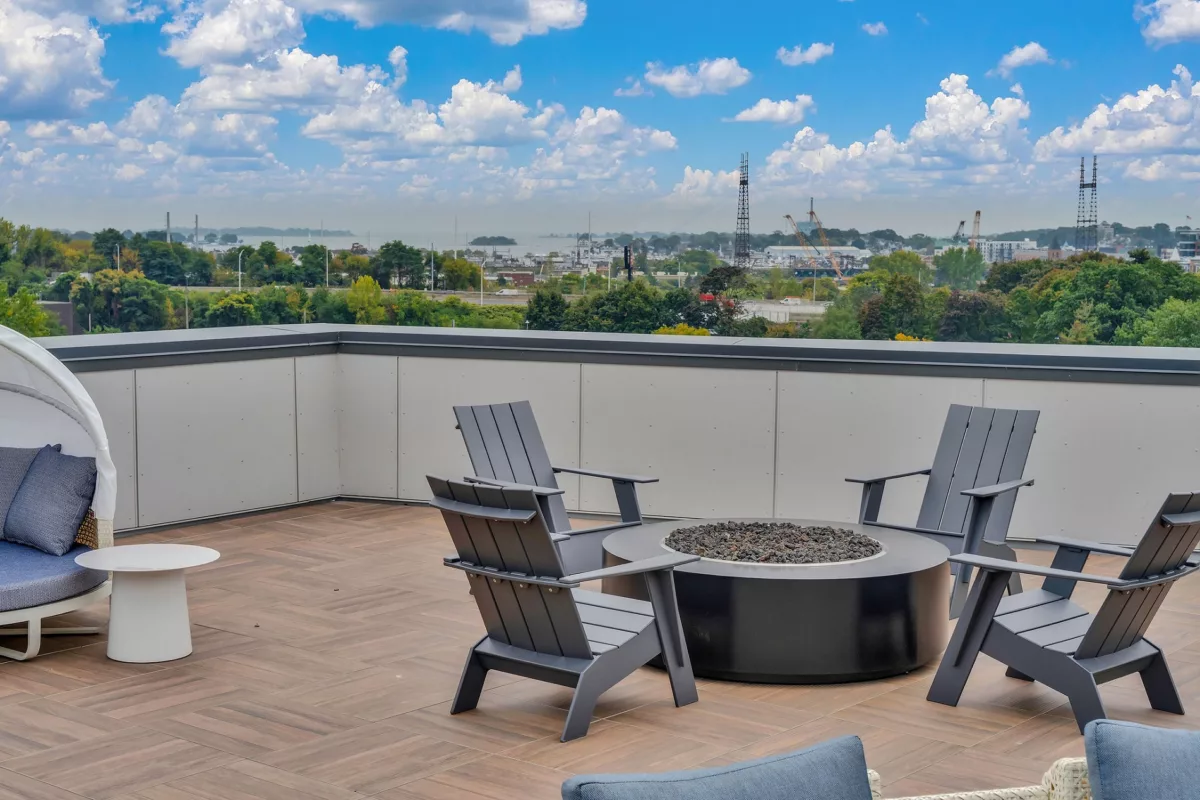 Rooftop lounge with Adirondack chairs, fire pit, and city view.