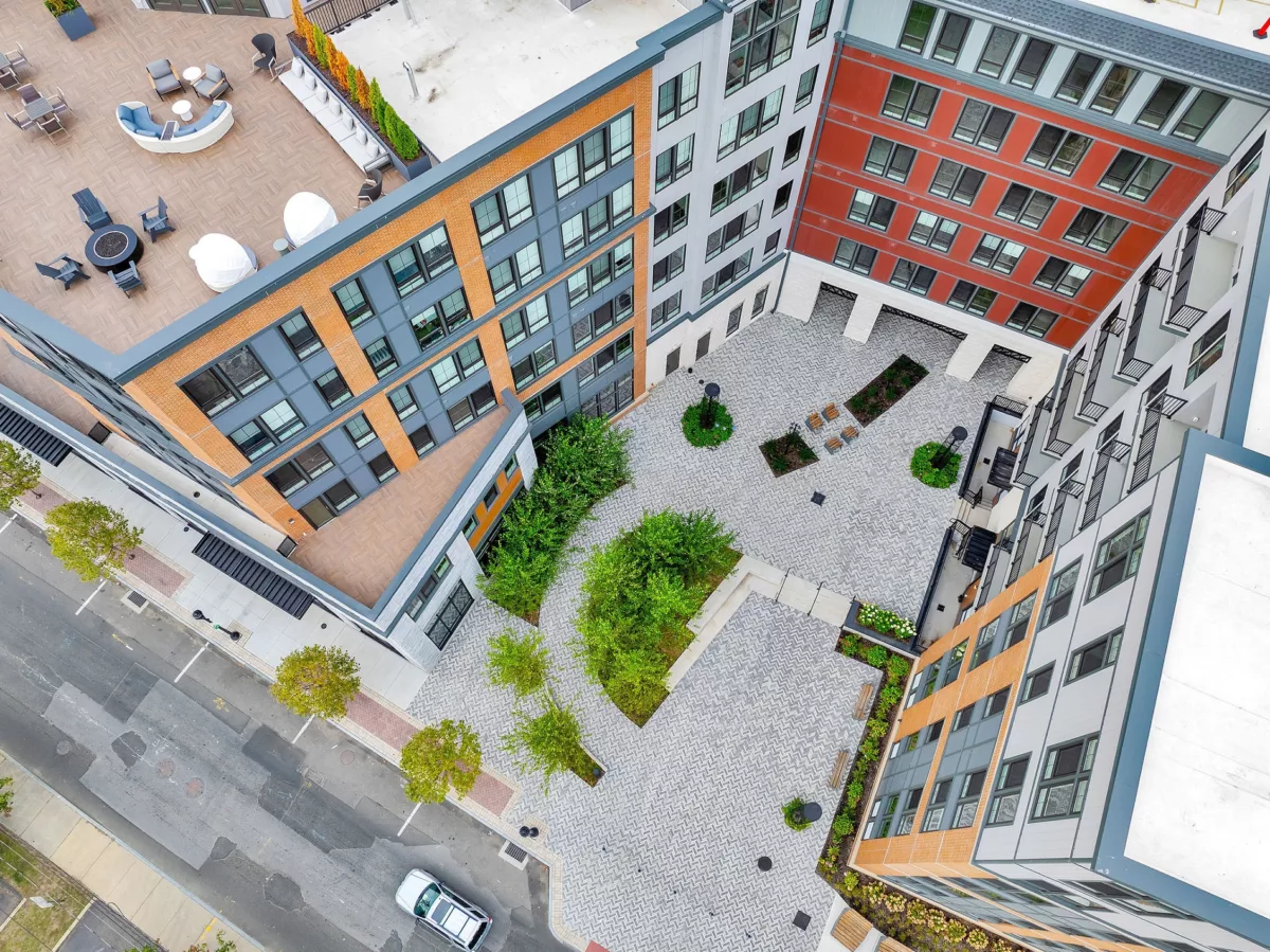 Aerial view of multi-story buildings surrounding a landscaped courtyard with seating and walkways.