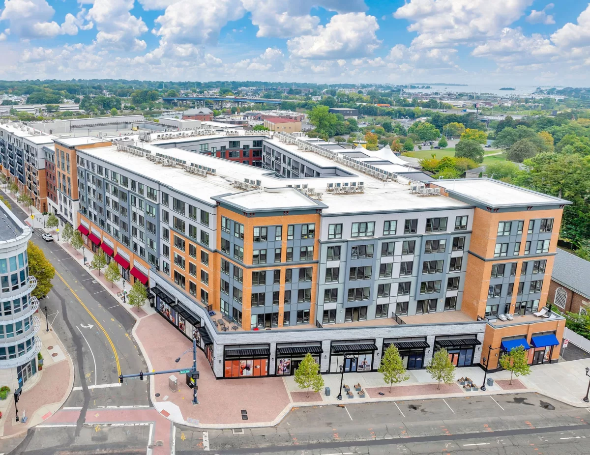 Aerial view of a multi-story apartment building with retail space on the ground floor.