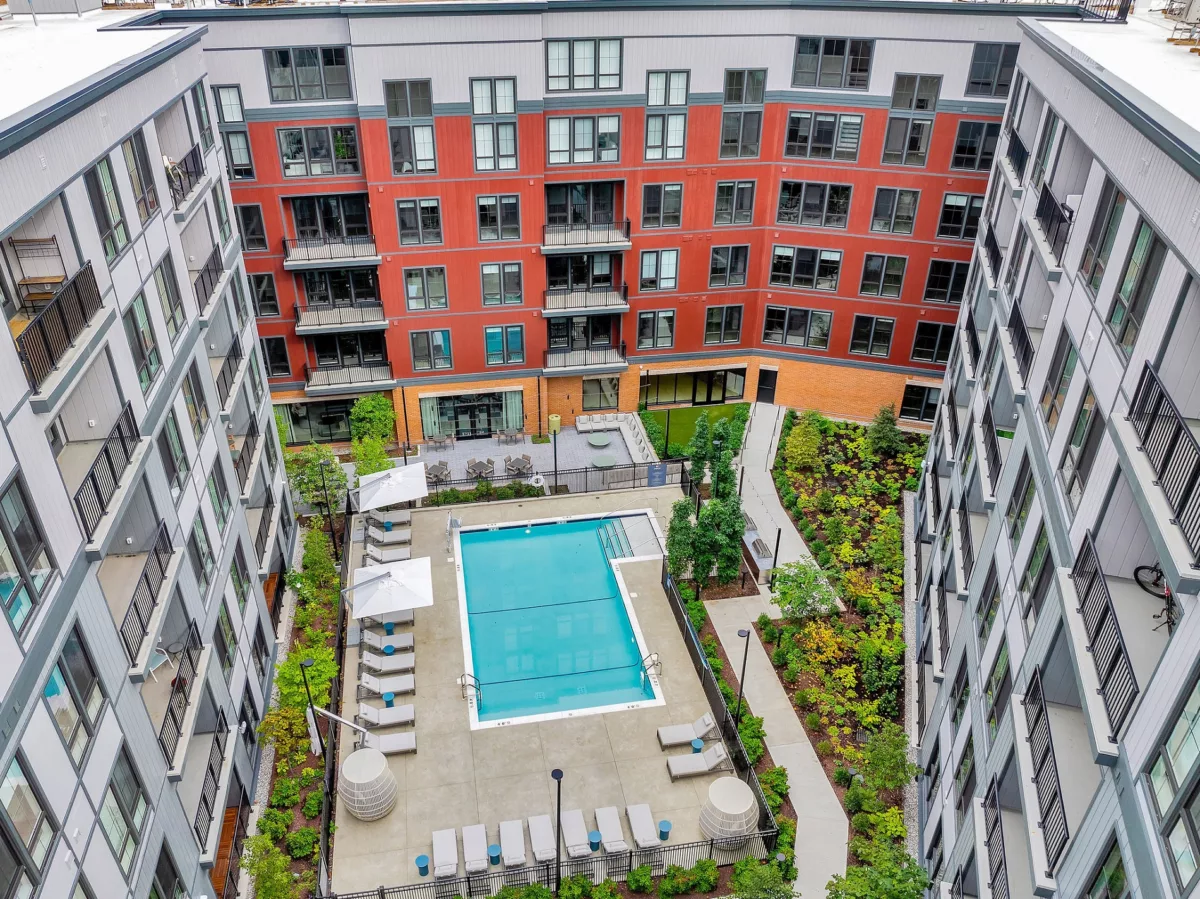 Aerial view of a pool and lounge area surrounded by multi-story apartment buildings.
