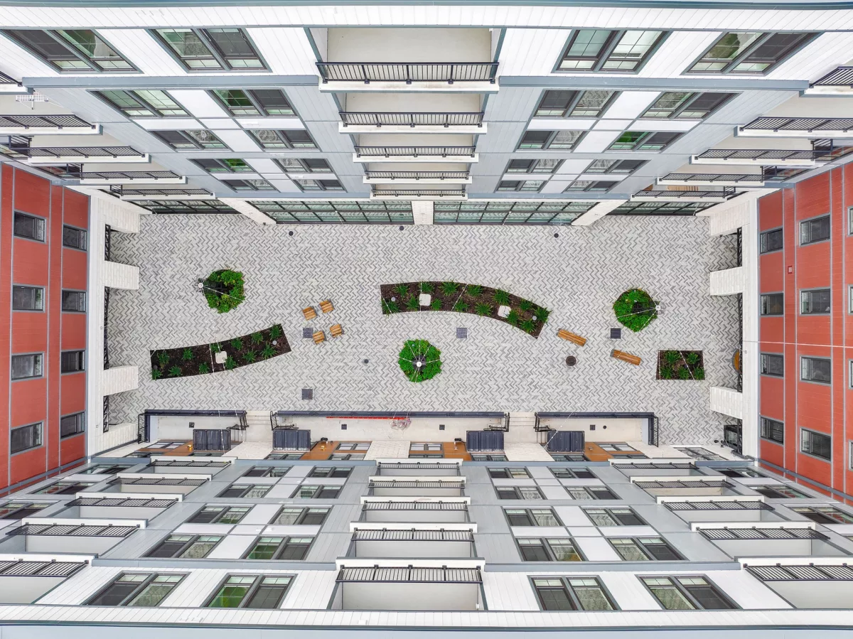 Aerial view of courtyard with herringbone pavers, planters, and seating between buildings.