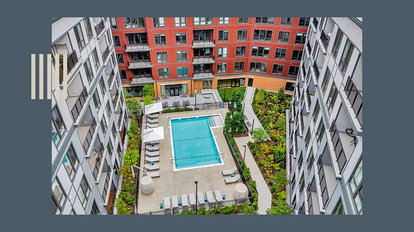 Aerial photo of an apartment building courtyard with a pool surround by a blue border.