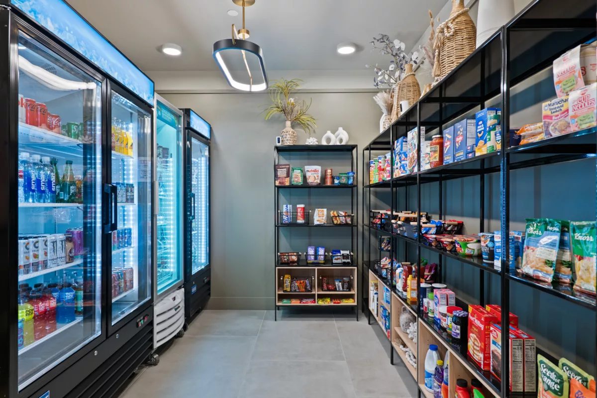 Market with refrigerated drinks and shelving stocked with snacks and household items.