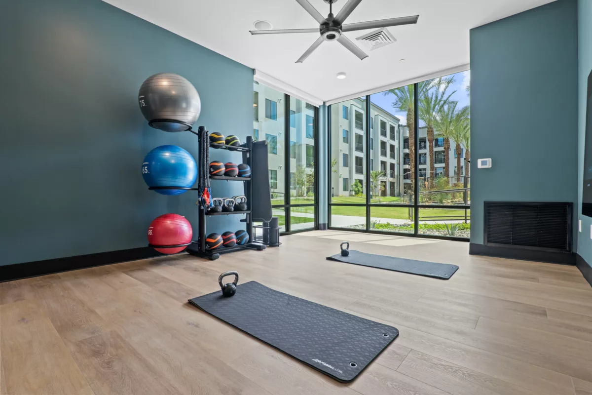 Fitness center with exercise balls, kettlebells, mats, and large windows.