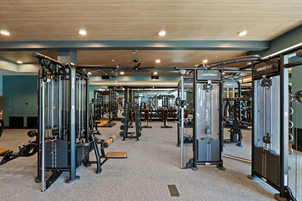 Fitness center with weight machines, free weights, and mirrored walls.
