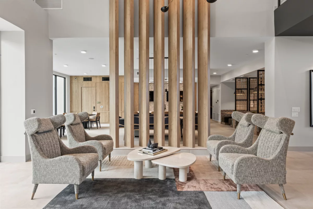 Lounge area with four upholstered chairs, stone coffee table, and wood slat divider.
