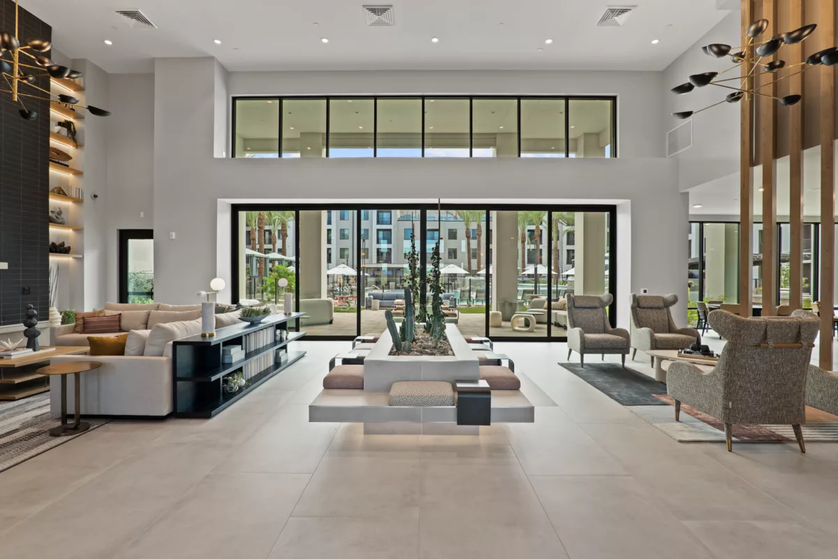 Modern lobby with lounge seating, tile floors, and large windows overlooking outdoor amenities.