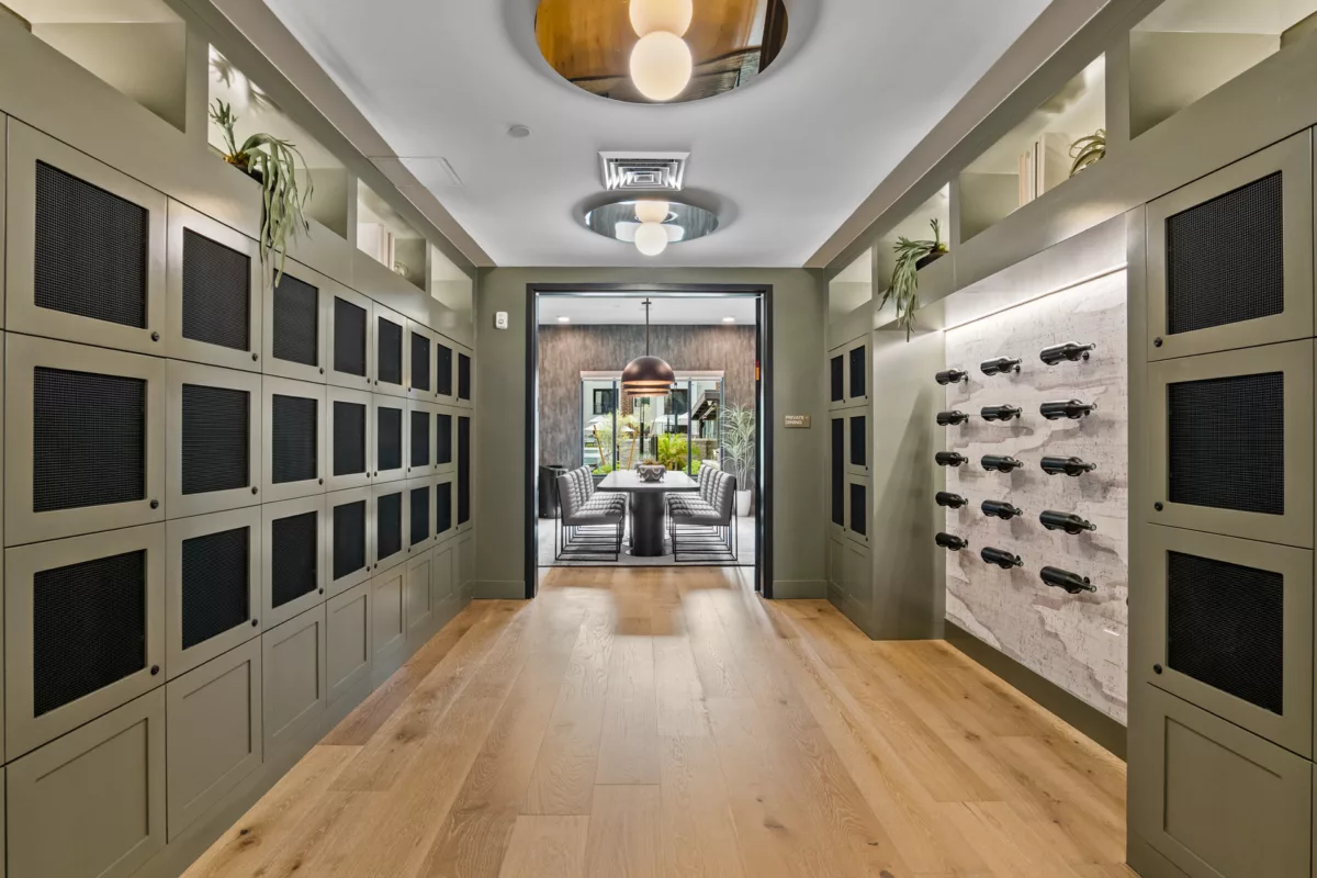 Hallway with lockers, wine storage, and view into private dining room with table and chairs.